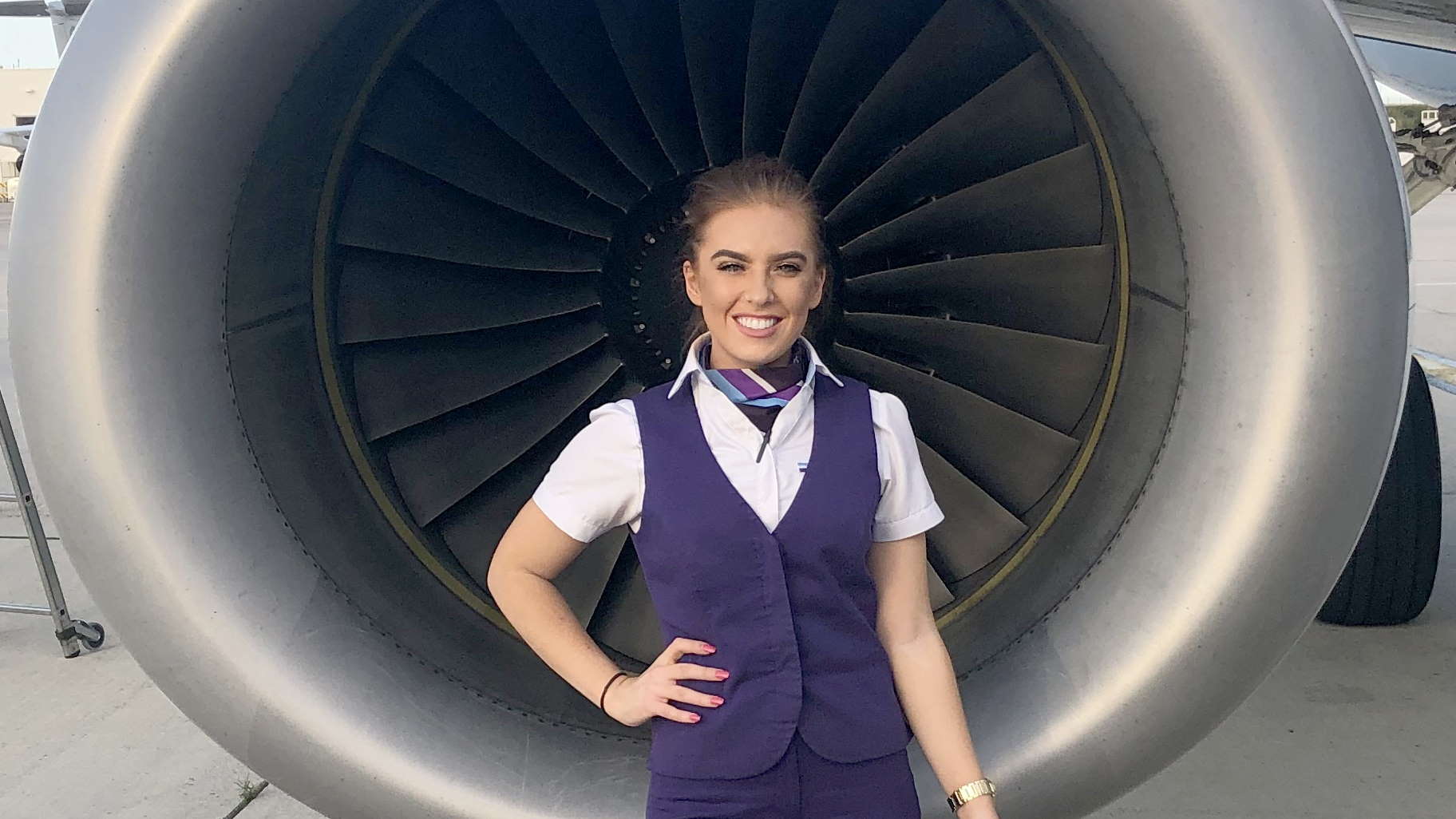 Student stands in front of a jet engine